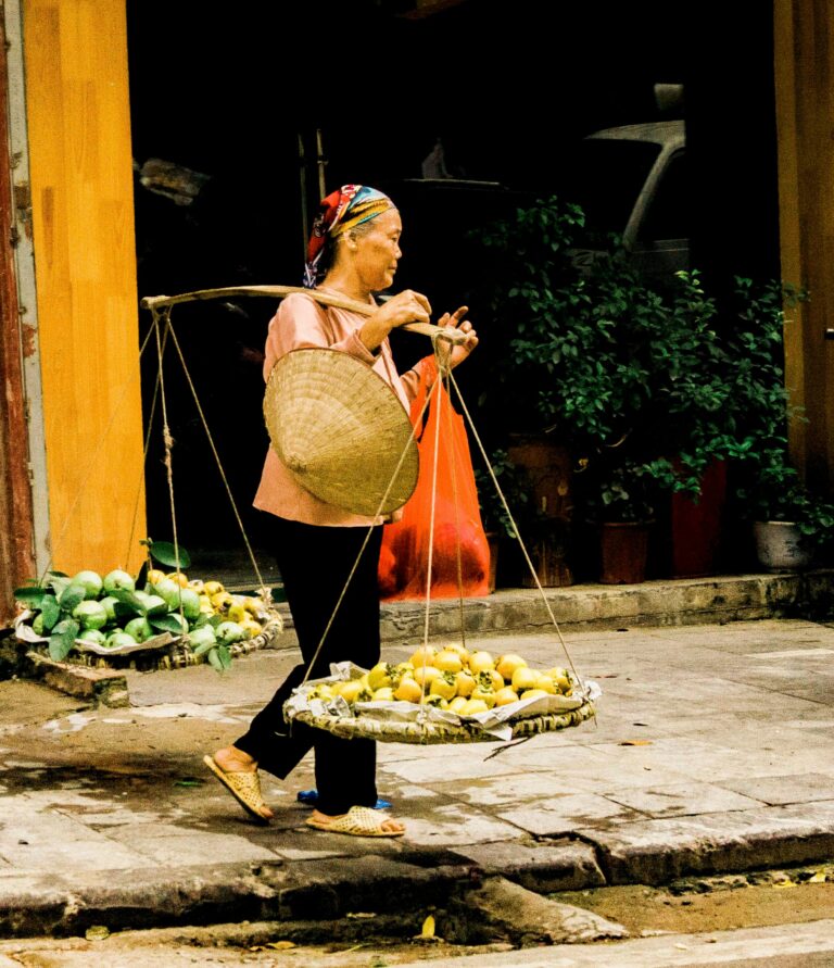 Elderly woman selling fresh fruits at an outdoor market, showcasing traditional commerce.